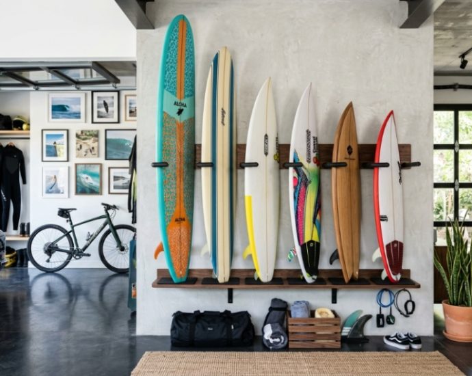 Vertical wood wall rack holding three surfboards inside a bright room.